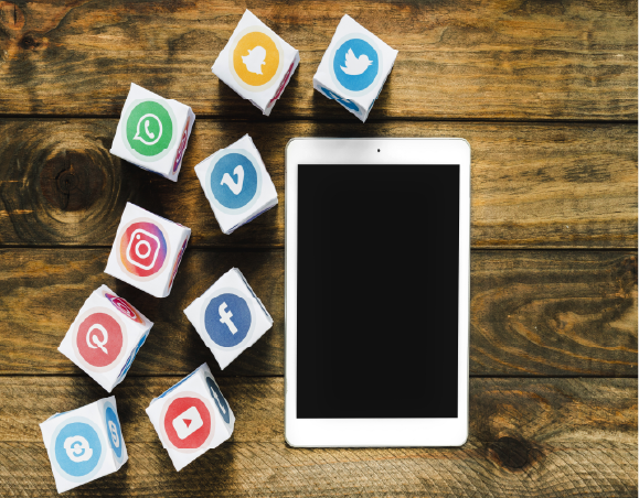 Photo d'une tablette avec des réseaux sociaux sous forme de dé à gauche il y a Snapchat, Facebook, X, Pinterest, Instagram, Youtube et autres